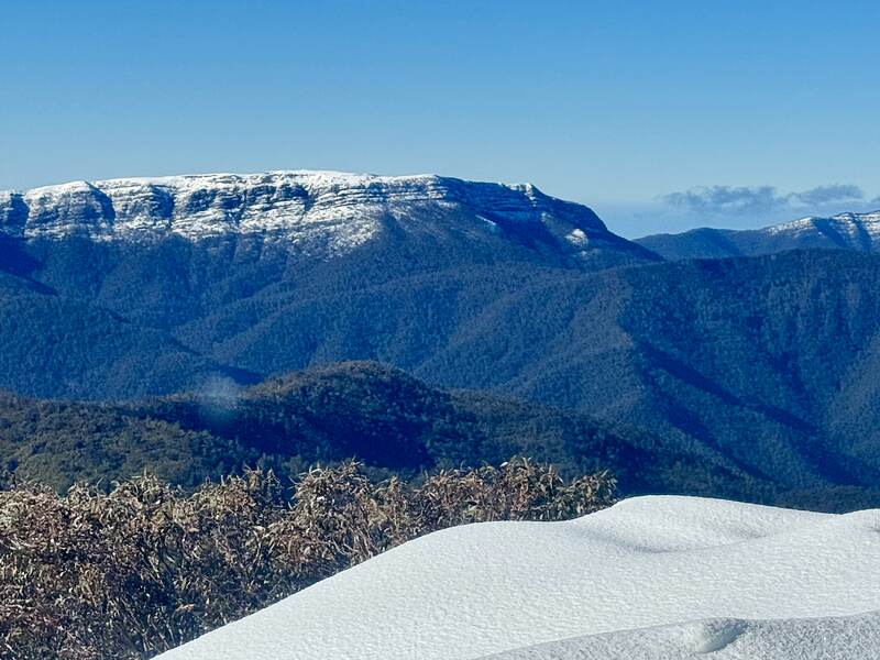The escarpment across the valley, its cap under fresh snow, forested ridges below.
