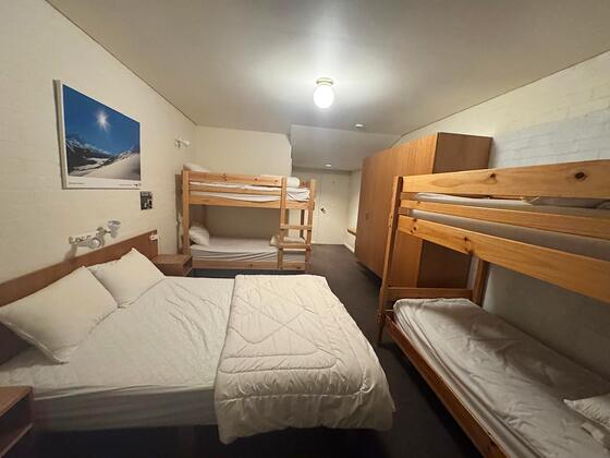 Room 5: queen bed with two single-over-single bunk units and a tall wardrobe.