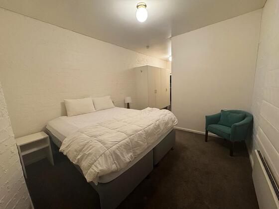 Room 10: king bed with wardrobe, armchair and a radiator.